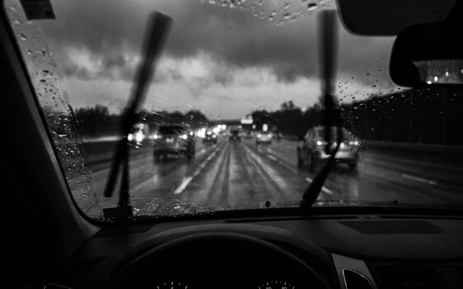 Dashcam view of a wet highway at night with taillights ahead