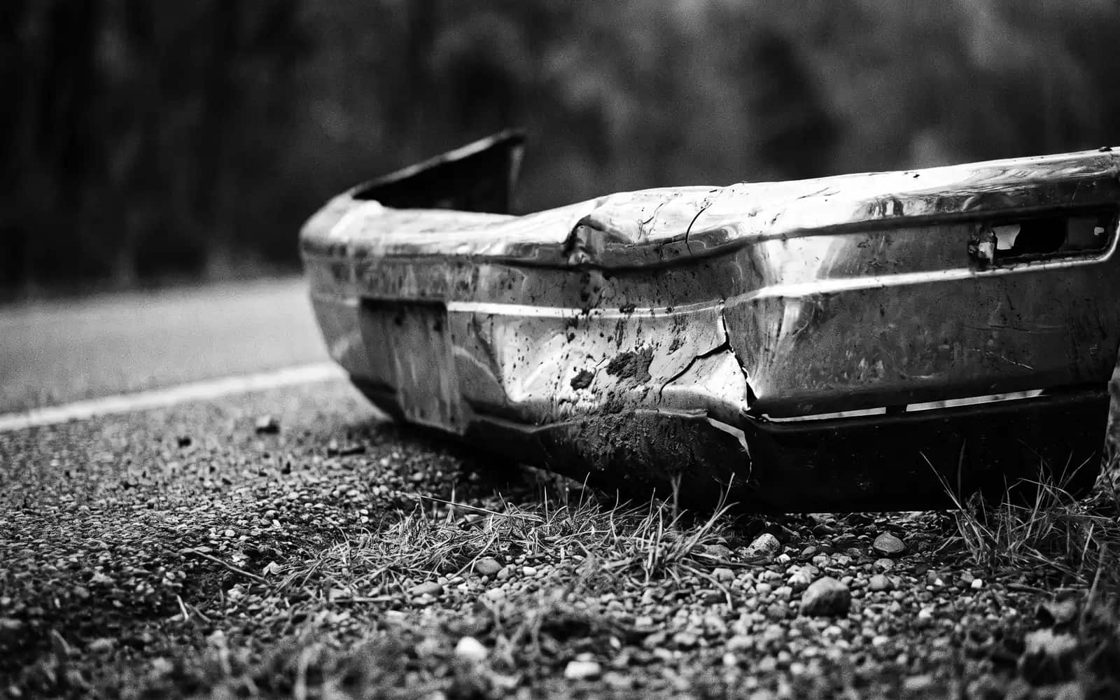 Close-up of a damaged car bumper on a road shoulder