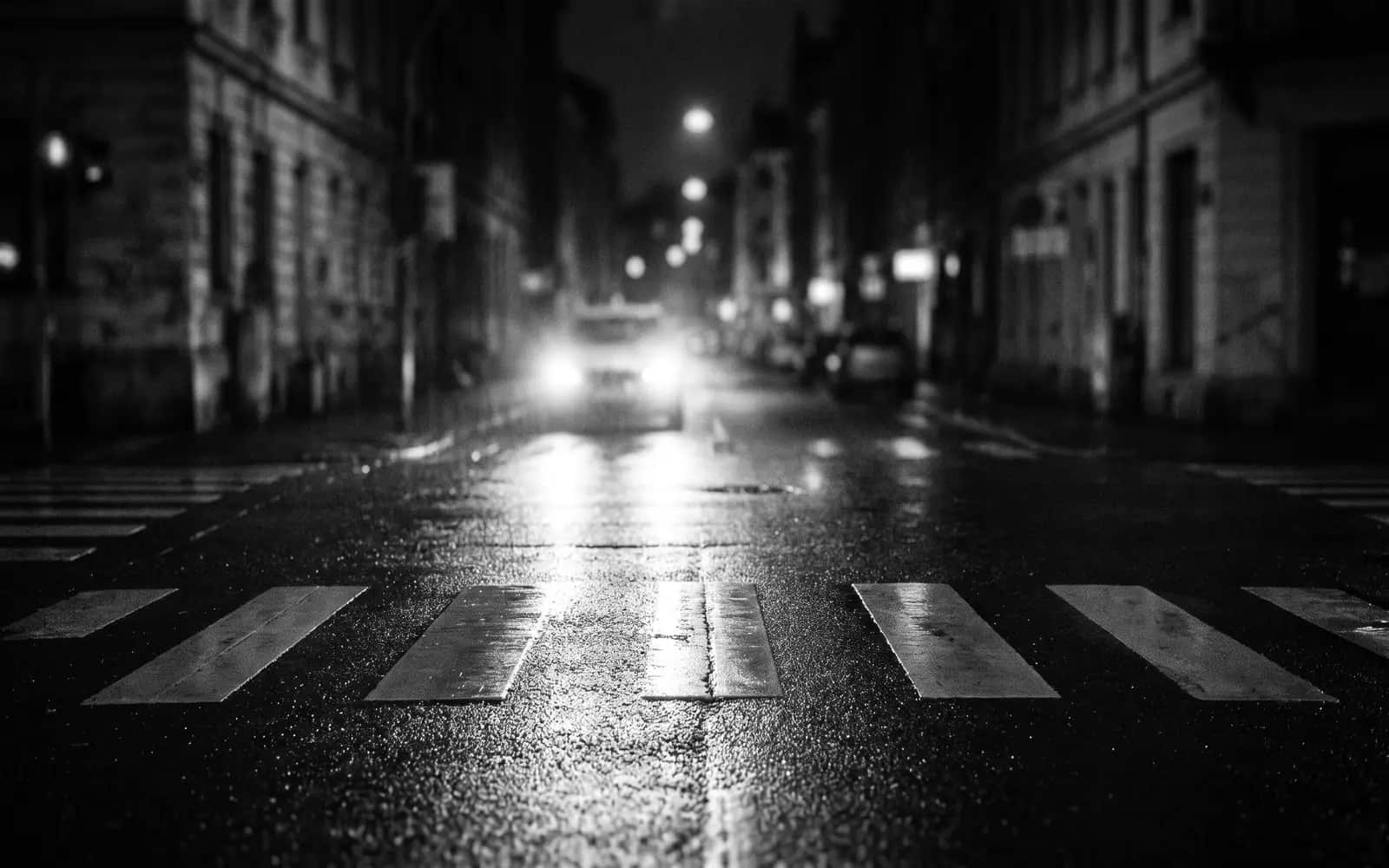 Pedestrian crosswalk at night with approaching headlights